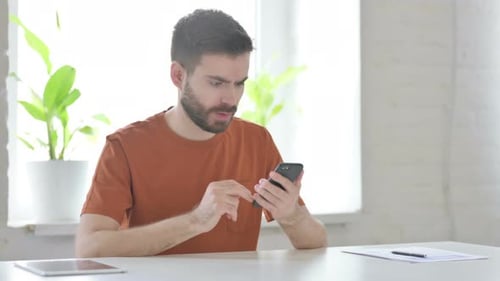 Man Using Smartphone Surprised and Frustrated in Home