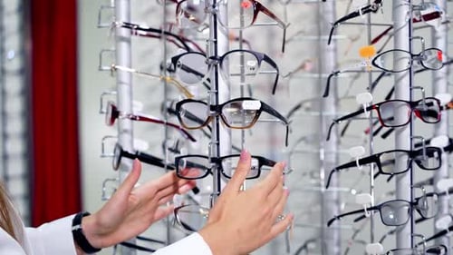 Young female choosing eyeglasses in the store