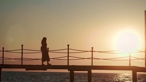 Lonely Female Traveler Walking Pier Contemplating Beautiful Seascape at Sunset with Big Bright Sun