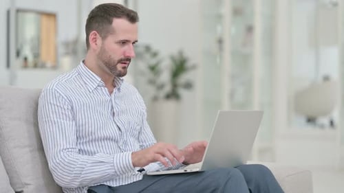 Man Celebrating Success Using Laptop Indoors
