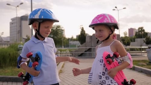 Cute Little Children in Helmets Walking in the Park with Skateboards