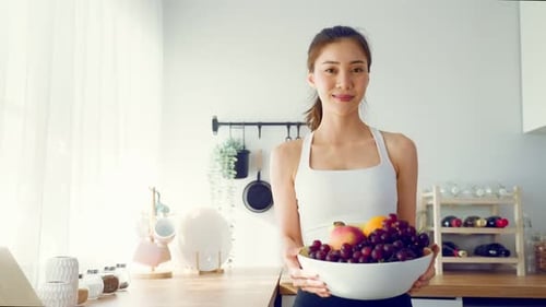 Smiling Woman Holding Bowl of Healthy Fruit
