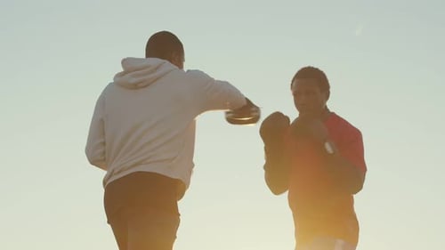 Two Black Man are Training to Boxing Outdoors Against Background Sky Side View