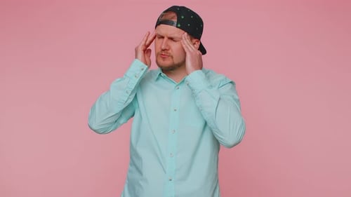 Man Experiences Headache Against Pink Backdrop