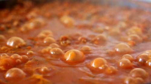 Closeup Macro of Rich Red Tomato Vegetable Sauce Boiling in Saucepan in the Process of Cooking Tasty
