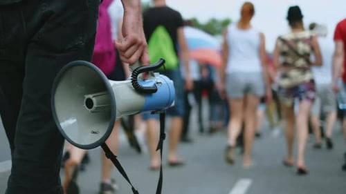 Person with Megaphone Leads a Walking Crowd