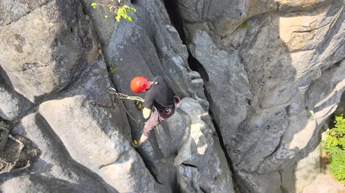 Young Man Climbing Steep Wall of Rocky Mountain