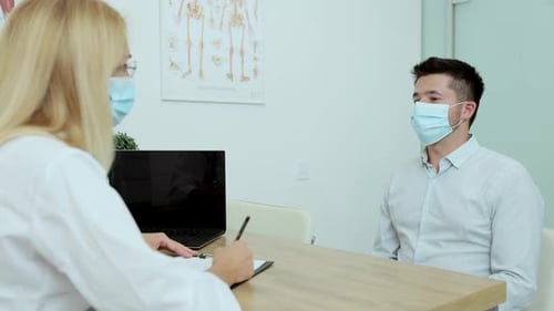 In Doctor Office Man Patient in Medical Mask Talks to His Female Doctor