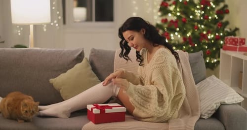 Woman Opening Christmas Gift on Couch