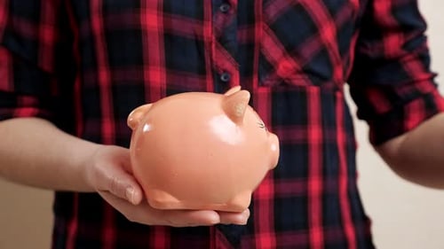 Woman Holds Piggy Bank on Palm and Throws Coin Inside