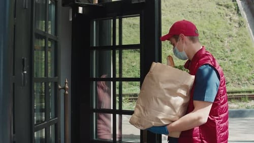Delivery Person Handing Grocery Bag To A Woman
