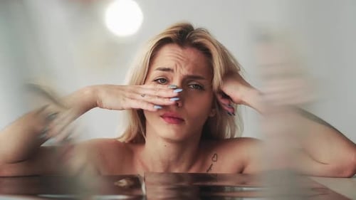 Sad Young Woman with Tattoos Resting Chin on Hands