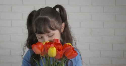 Smiling Child with Tulips Bouquet Against Brick Wall