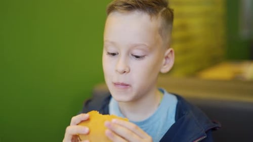 Boy Enjoying a Burger in Fast Food Restaurant