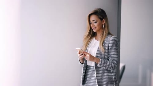 Businesswoman Sending Message with Smartphone in Office