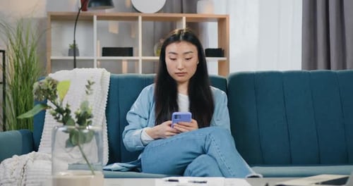 Young Woman Using Phone While Sitting on Sofa