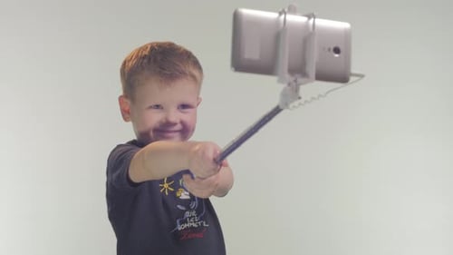 Child Smiling Holding Tablet on Selfie Stick