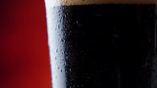 Dunkles Bier Nahaufnahme. Pint von Cold Craft Beer Rotation. Ein Glas Bier mit Wassertropfen.