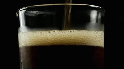 Dark Liquid Being Poured into Glass with Ice
