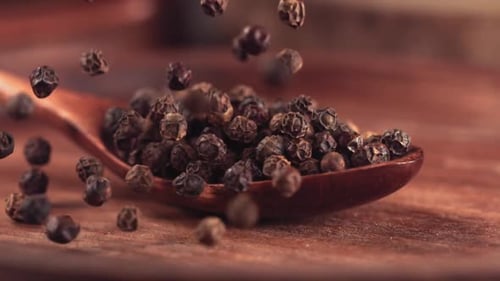 Falling Black Peppercorns Filling Wooden Spoon