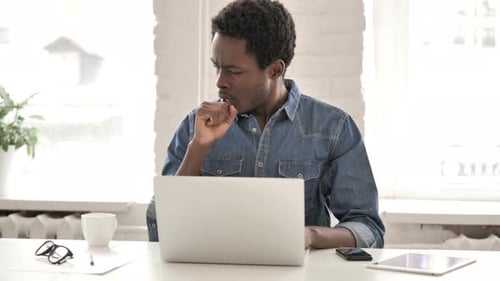 Man Coughs While Working at Laptop Indoors