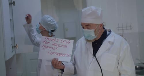 Doctor Shows to Camera Inscription "Thanks USA for Vaccine Against Coronavirus"