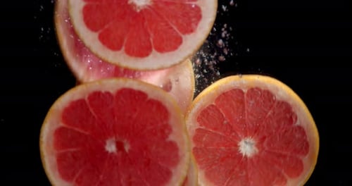 Grapefruit Slices Falling Into Water on Black Background