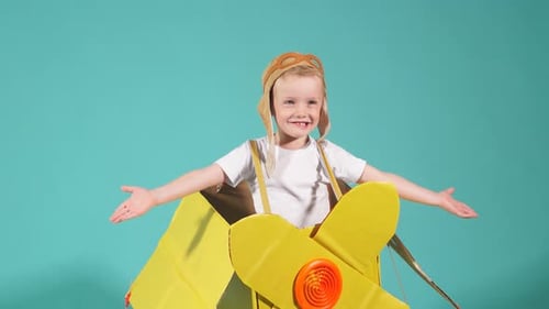 Netter kleiner Junge trägt gelben Spielzeug-Flugzeugständer isoliert in Blau