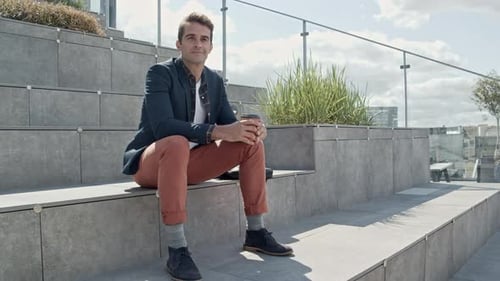 Man Sits and Drinks Coffee on Rooftop