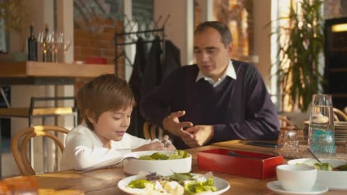 Father and Son Sit at Wooden Table and Talk