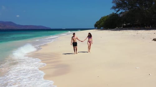 Beautiful Man and Woman on Romantic Honeymoon Enjoy Luxury on Beach on White Sand