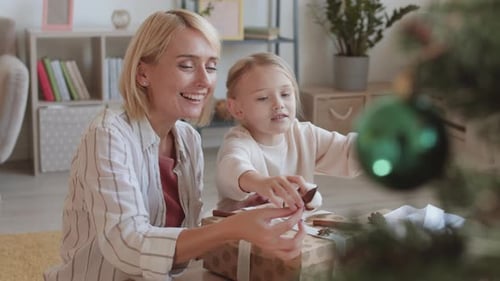 Woman and Child Decorating Christmas Presents Together