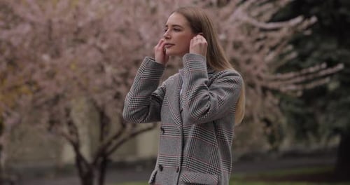 Woman Puts in Wireless Earbuds Outside