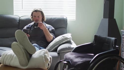 Man Relaxes on Couch With Phone and Beverage