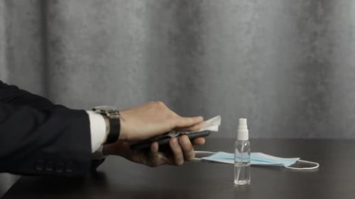 Man in Suit Cleans Phone with Disinfectant