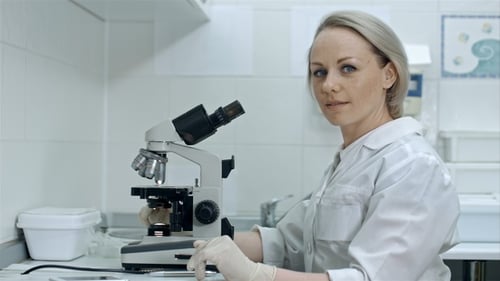 Female Scientist Working with Microscope in Bright Lab