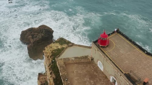 Lighthouse on Cliffside Overlooking Crashing Ocean Waves