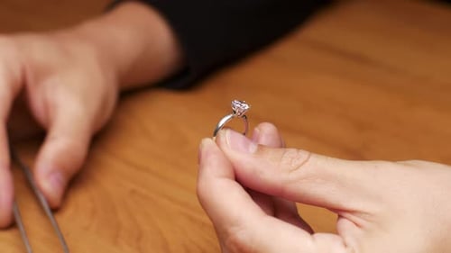 Nahaufnahme eines Juweliers fügt einen Diamanten in den Ring ein
