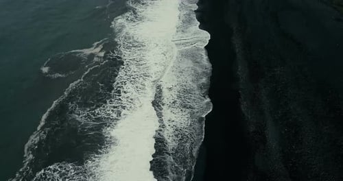 Aeial View of the Wave Coming on the Shore of the Black Volcanic Beach in Iceland. Mountain on the