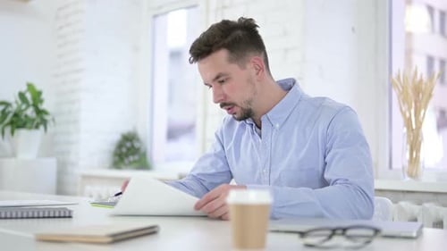 Young Adult Reviewing Documents in Modern Office