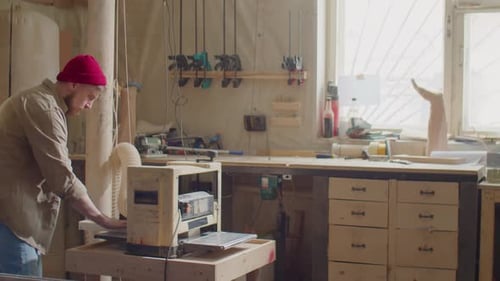 Woodworker Using Thickness Planer in Workshop