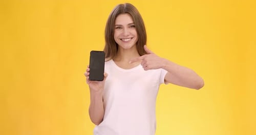 Woman Holding Smartphone and Pointing at Screen