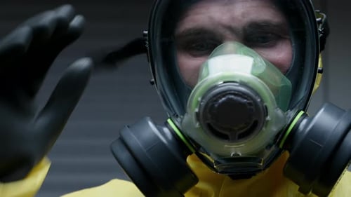 Person in Hazmat Suit Adjusts Respirator