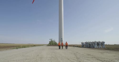 Anonymous Colleagues Walking Towards Windmill in Countryside