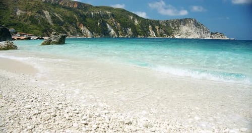 Clear Sea Waves Splashing on Peaceful White Beach with Pebbles Seascape with Rocks in Background