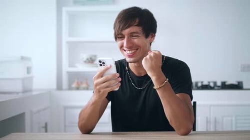 Excited Man Cheers While Looking at Smartphone