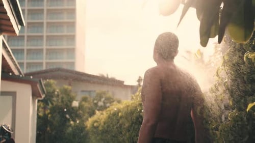 Man Enjoying Outdoor Shower in Tropical Setting