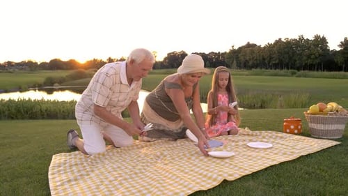 Family Picnic on Grassy Lawn at Sunset