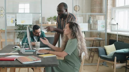 Afro Man and Caucasian Woman Discussing Project on Computer in Office
