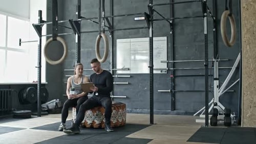 Woman Listening Instructions of Male Coach in Cross Training Gym